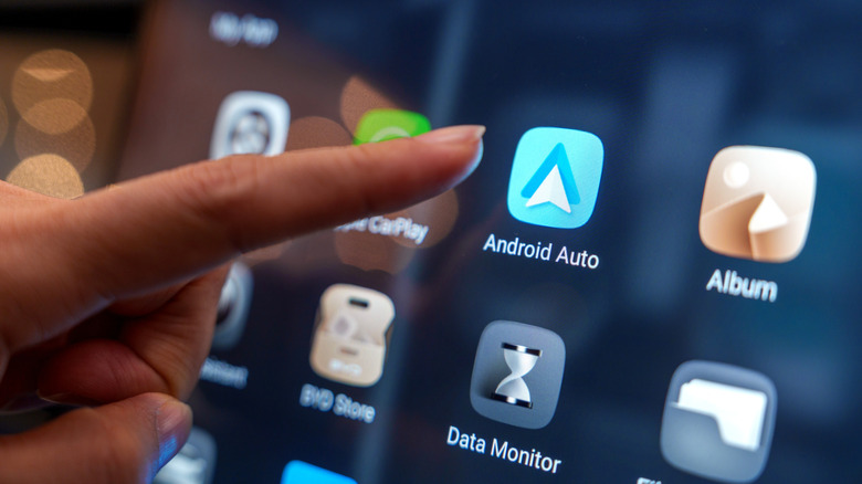 A lady touching the Android Auto logo on the car's touchscreen