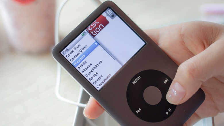 The hand of a person using an iPod classic to select a song playlist in a cafe.