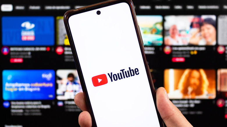 YouTube on phone in front of screen with video list