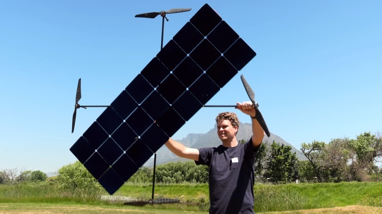A young man holding up a large solar-powered drone