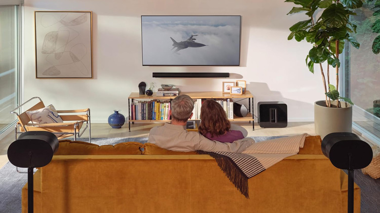 A living room setup with Sonos speakers and two people