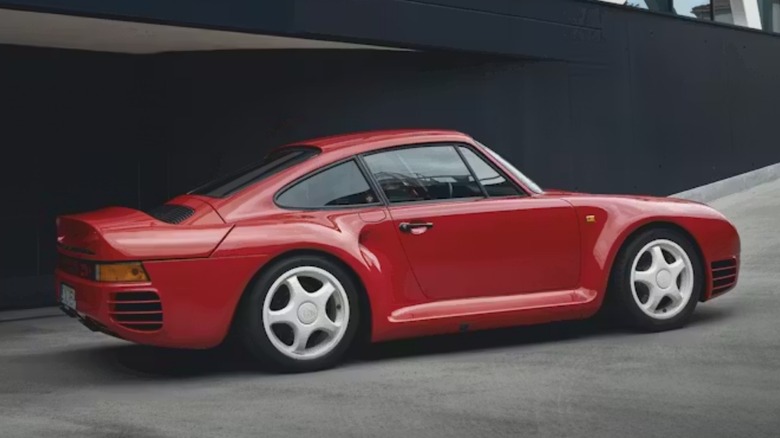 Red Porsche 959 parked in front of a black wall