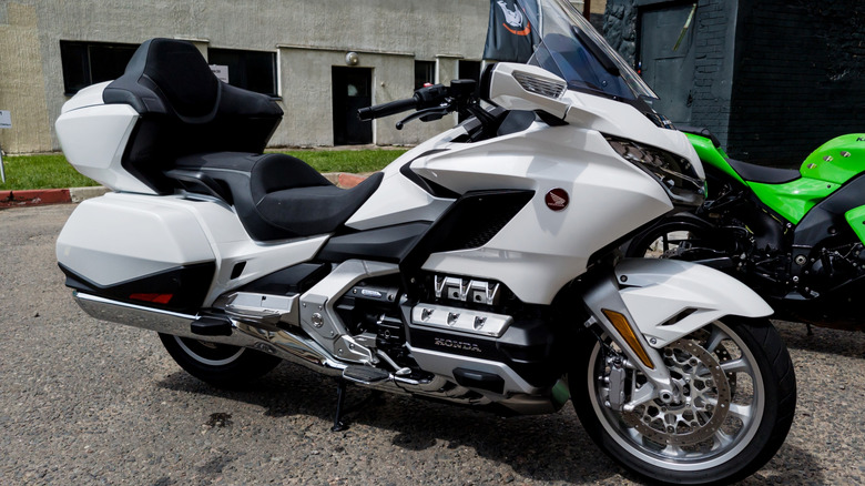 A white Honda Gold Wing Motorcycle parked on a street with other bikes.