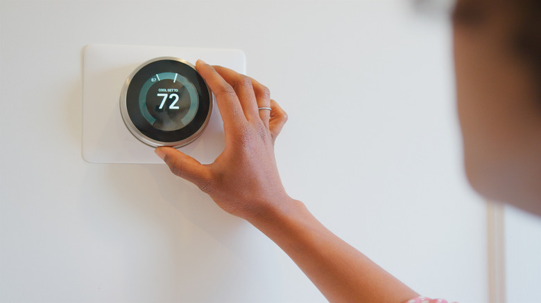 User setting thermostat on wall.