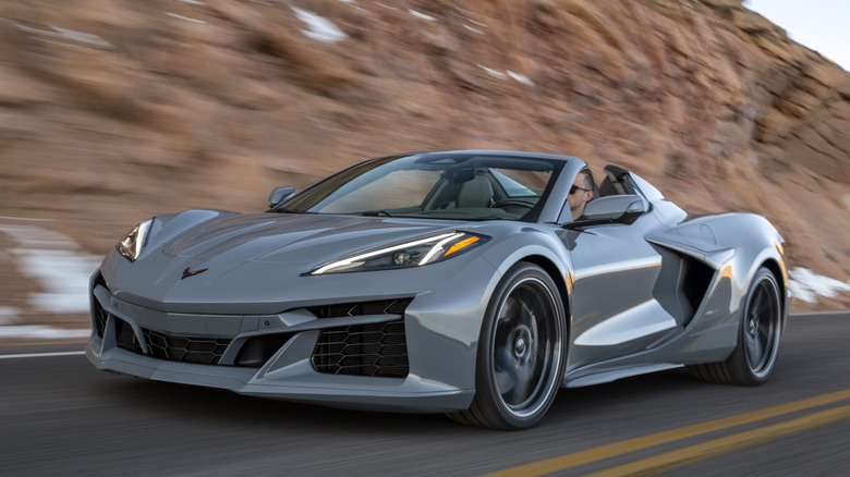 Front 3/4 view of Corvette E-Ray on a road in a mountainous setting.