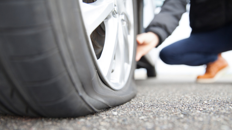 A person checking a flat tire on the road.