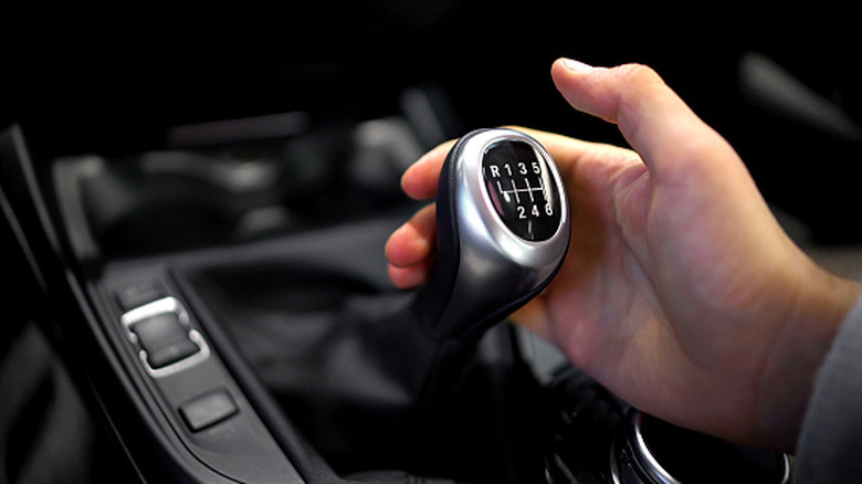 A person shifting a manual transmission on an old BMW.