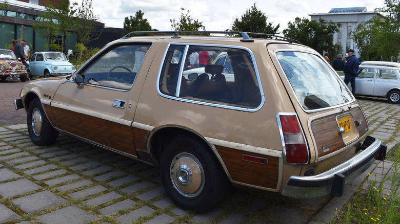 Rear 3/4 view of AMC Pacer Wagon in urban setting, cream exterior with wood panels and cream steelies, Dutch plates